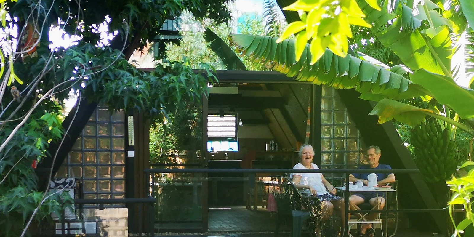 Two guests laughing over breakfast on the terrace of the A-frame house