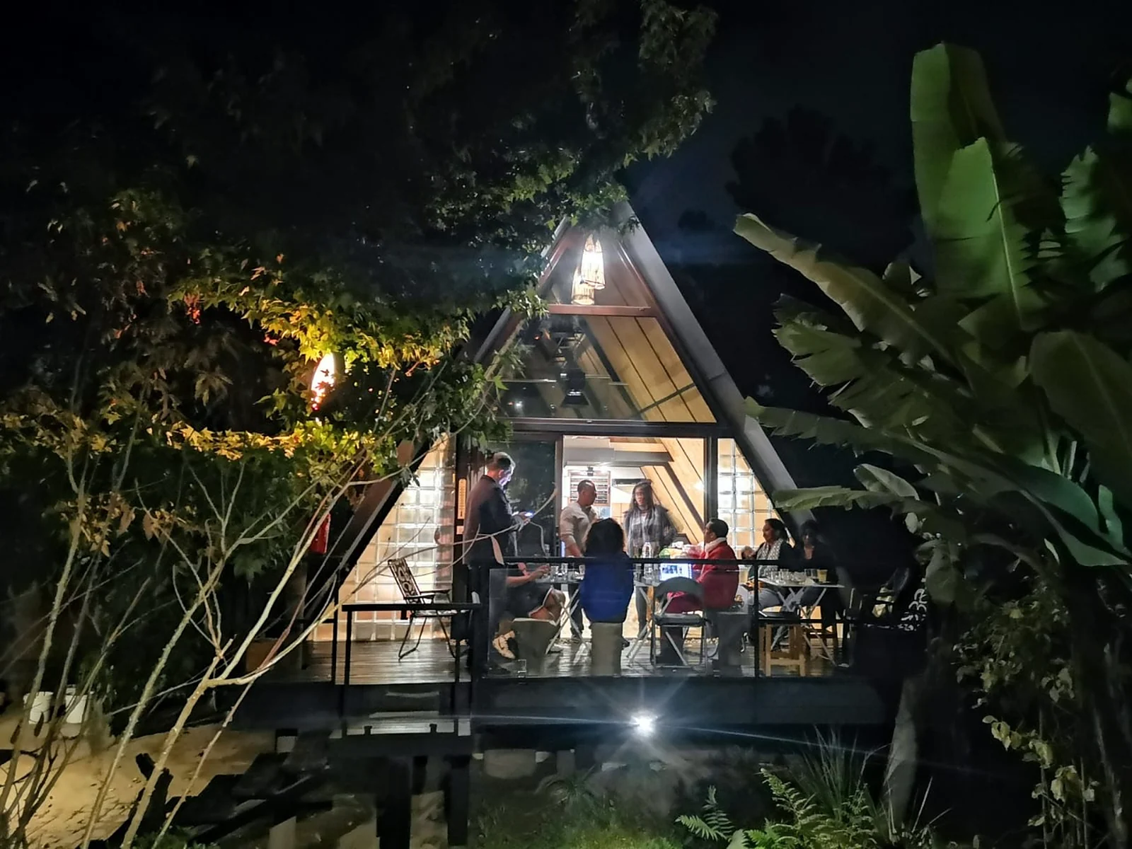 Guests at dinner on the lit terrace of the Cinéroutes B&B in Andoharanofotsy at night