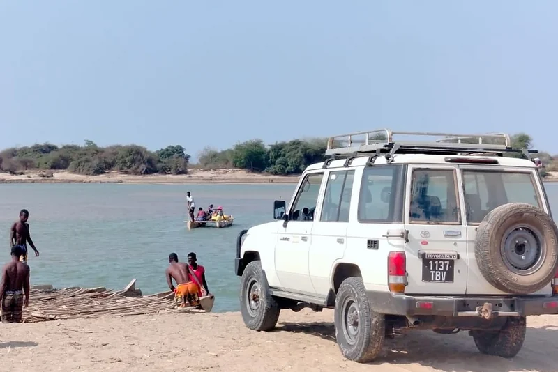 Le Toyota Land Cruiser 76 blanc attend sur la rive pendant que des villageois préparent le bac en pirogues