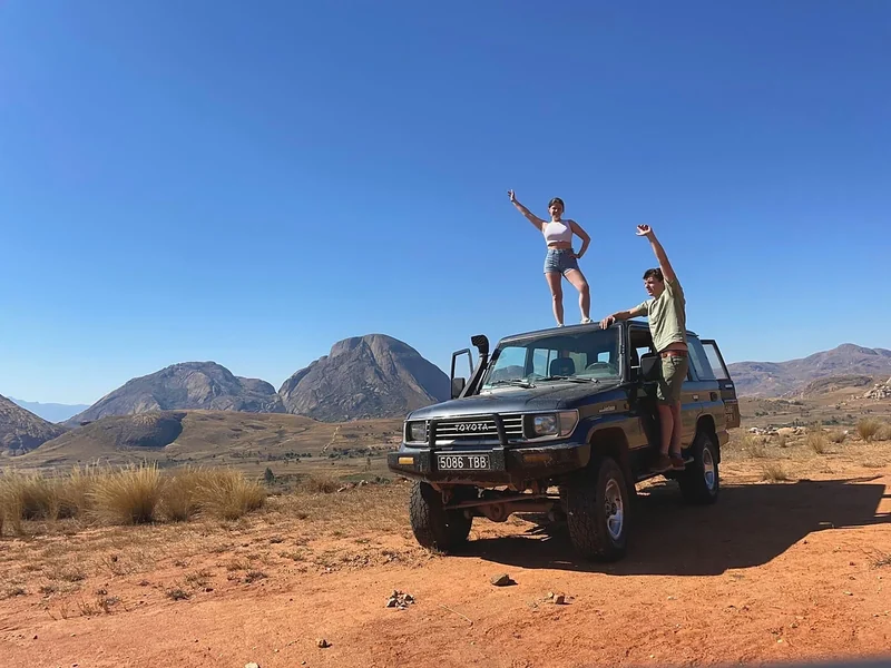Deux voyageurs sur le Land Cruiser LJ79 devant des dômes de granit