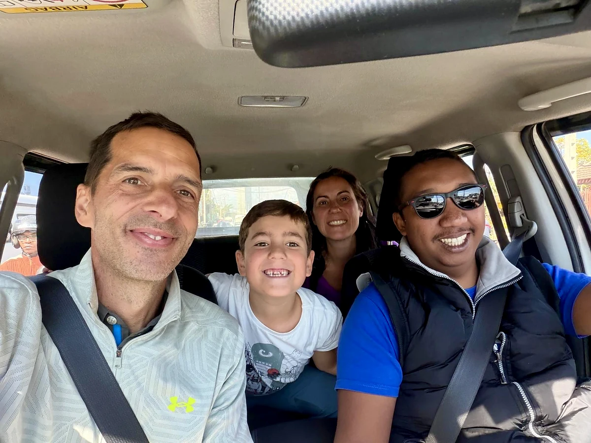 L’un de nos chauffeurs sourit au volant avec une famille de voyageurs en road trip