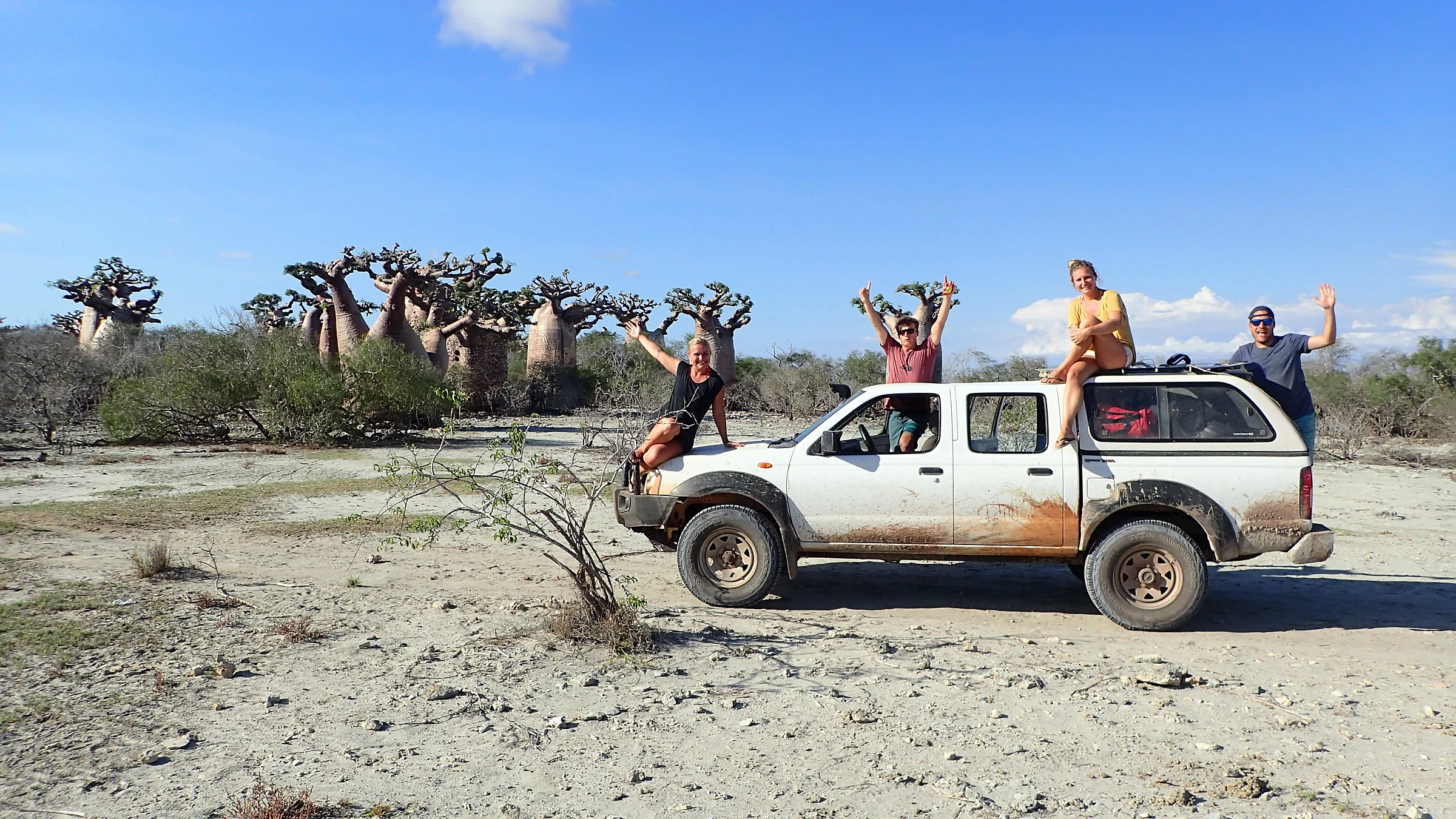 Quatre voyageurs heureux sur leur Nissan 4x4 de location parmi les baobabs de la côte ouest de Madagascar