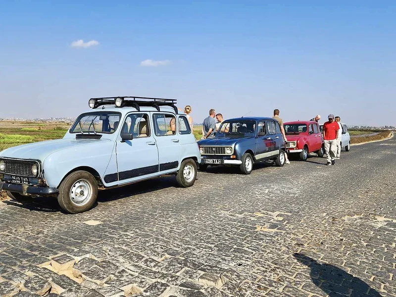 Three Renault 4s parked along a cobbled road