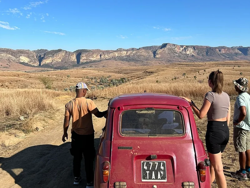 Travellers with a pink Renault 4 on a dusty track