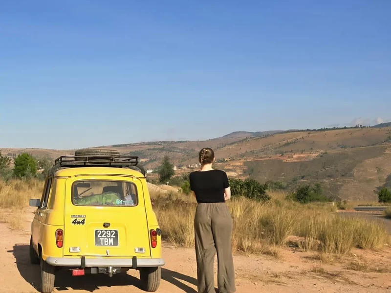 Een reiziger bewondert het uitzicht naast de gele Renault 4 Sinpar